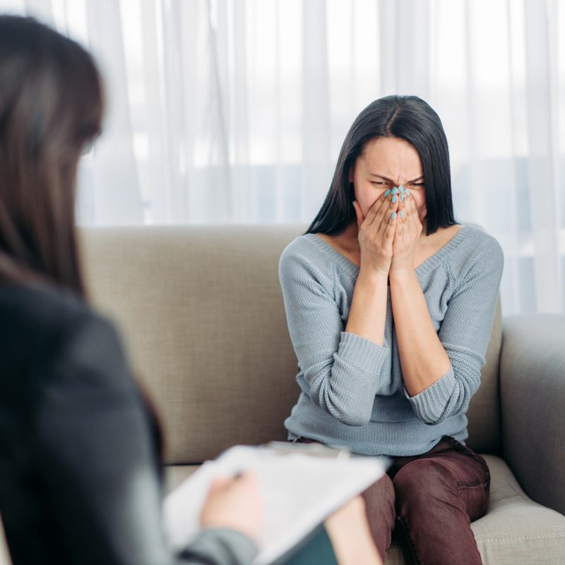 Female patient sitting on sofa at psychotherapist