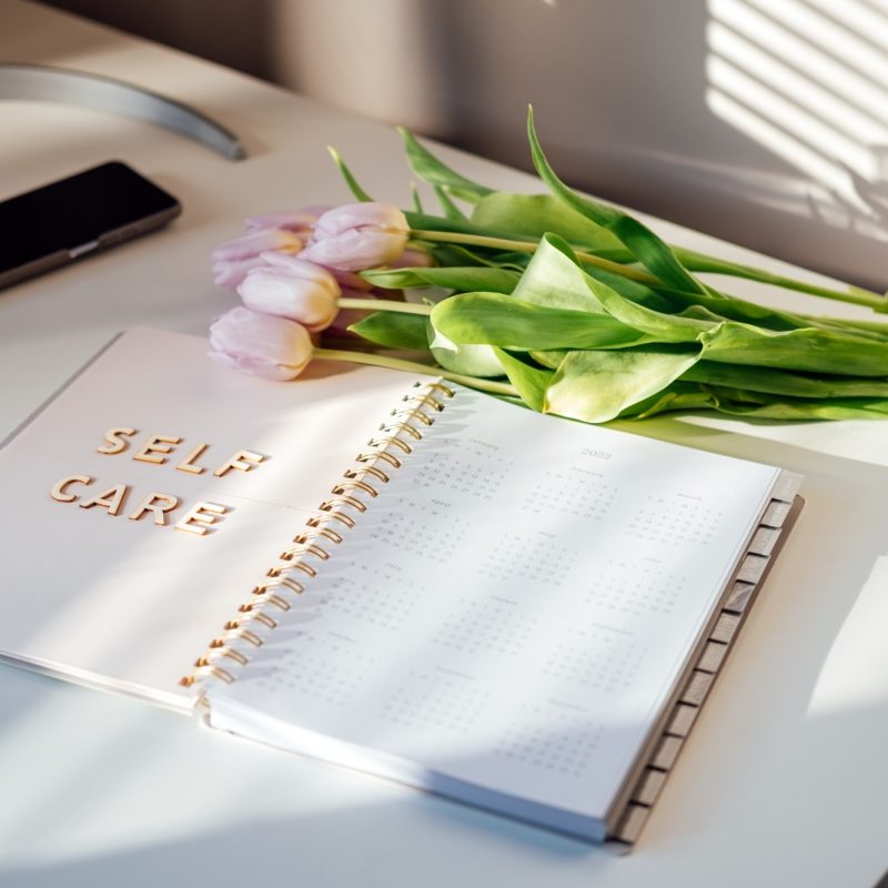 Self Care, wellbeing concept with open notebook, Self care word, tulip flowers on white table. Take care of yourself, Beauty, self care routine.