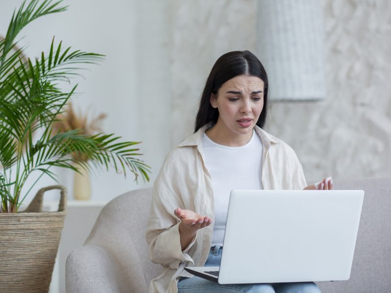 Online psychotherapy. A young worried woman is sitting at home with laptop